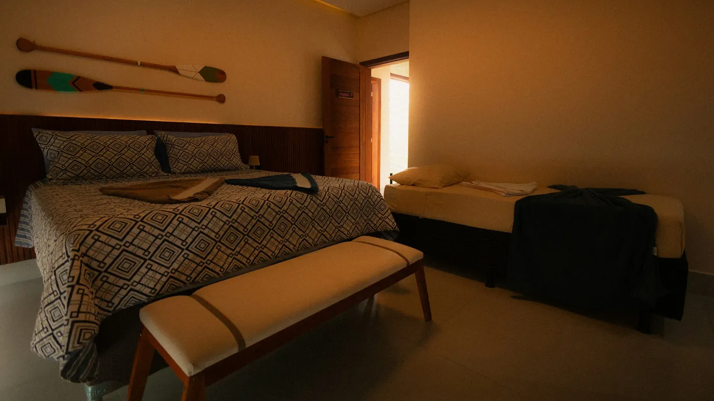 Ruime kamer met een tweepersoonsbed en een tweede bed in warm avondlicht