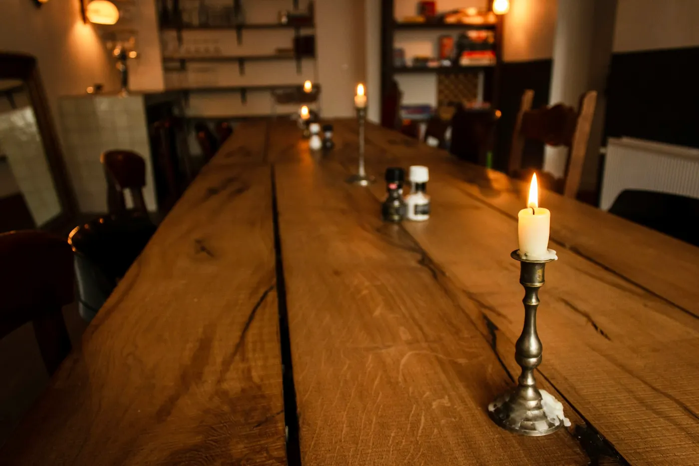 Een brandende kaars op een lange eikenhouten tafel