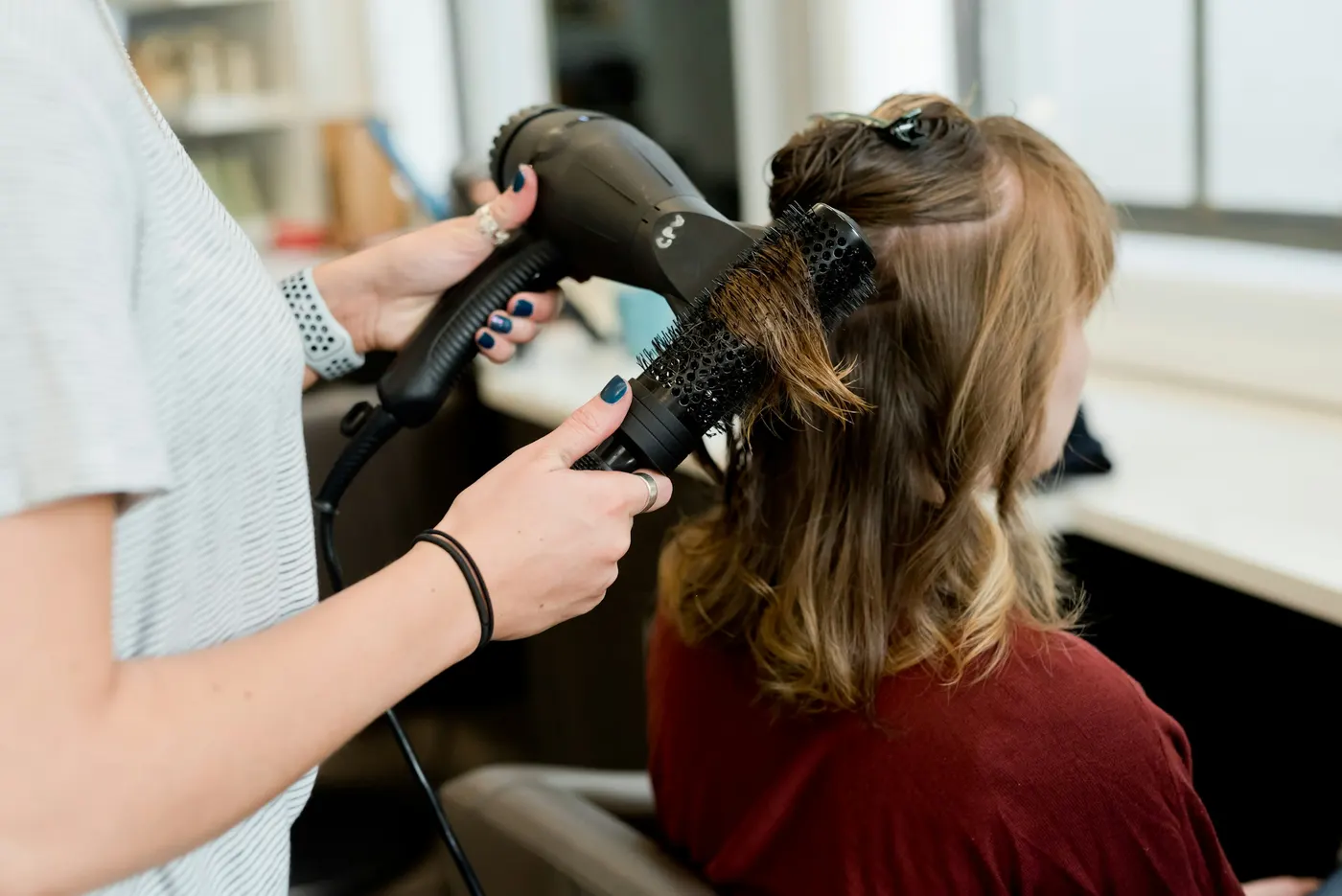 Een stylist föhnt halflang haar met een ronde borstel