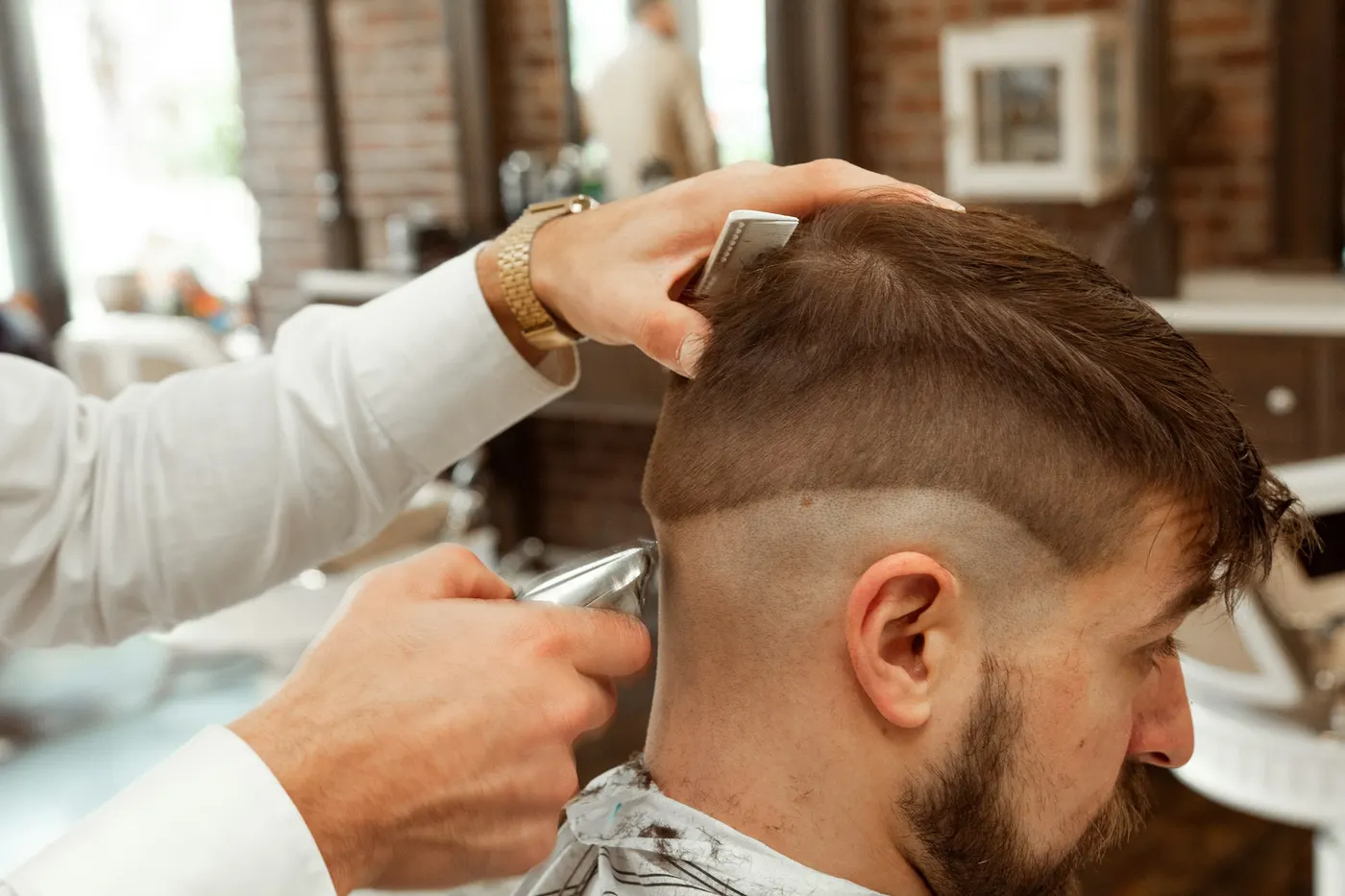 Een kapper knipt een fade bij een man met een baard